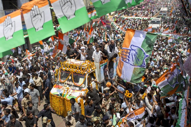 India’s ruling Congress party Vice President Rahul Gandhi (center wearing white without hat) waves to supporters in a street festooned with party flags during an election campaign rally in Varanasi in the northern Indian state of Uttar Pradesh on Saturday.   AP-Yonhap