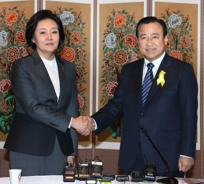 Lee Wan-koo of the ruling Saenuri Party and Park Young-sun of the main opposition New Politics Alliance for Democracy shake hands during a meeting at the Assembly building in Seoul, Sunday. (Yonhap)
