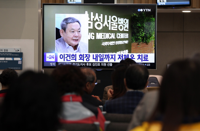 People watch TV news about Samsung chairman Lee Kun-hee’s hospitalization on Monday.  (Yonhap)