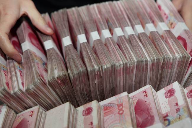 A teller counts notes in a bank in Ganyu county in east China’s Jiangsu province.   AFP-Yonhap