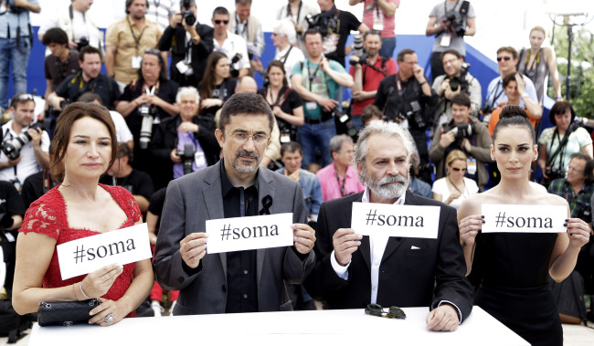 Actress Demet Akbag (from left), director Nuri Bilgle Ceylan, actor Haluk Bilginer and actress Melisa Soezen pose with signs reading “#soma,” a reference to Turkey’s worst mining incident, which took place last week, during a photo call for “Winter Sleep” at the Cannes Film Festival in Cannes on Friday.   AP-Yonhap