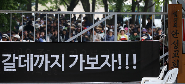 Members of the Christian cult led by Yoo Byeong-eon, the de facto owner of the sunken Sewol ferry’s operator, sit at the gates of their religious facility in Anseong, Gyeonggi Province, to restrict access following the prosecutors’ recent request of a preliminary arrest warrant for Yoo.   Yonhap