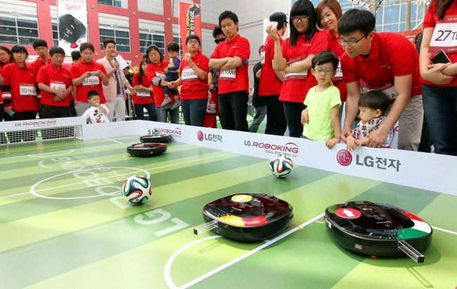 LG전자는 지난 18일 서울 용산구 아이파크몰에서 다음달 브라질월드컵에 참가하는 대한민국 축구 대표팀의 승리를 기원하는 ‘LG 로보킹 풋볼 챔피언십’ 행사를 개최했다. 행사에 참가한 시민들이 스마트폰으로 로봇청소기 ‘로보킹’을 조작해 축구를 하며 즐거워하고 있다. ［사진제공=LG전자］
