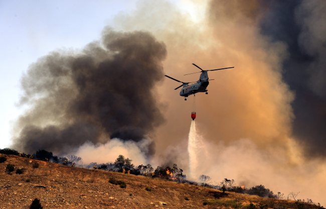 A U.S. military helicopter dumps water on a wildfire in San Marcos, California.   EPA-Yonhap