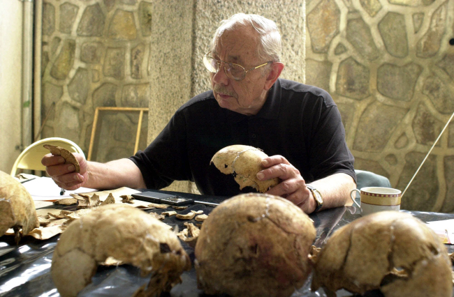 In a June 2, 2000, file photo, forensic anthropologist Dr. Clyde Snow of Oklahoma unites parts of a skull in San Salvador, El Salvador.   AP-Yonhap