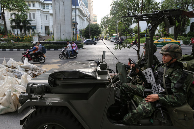 Motorists drive past Royal Thai Army soldiers stationed near luxury hotels on Ratchadamri Road in central Bangkok, Thailand, on Tuesday. (Bloomberg)