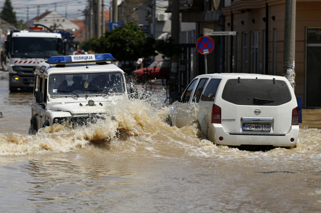 Police cars drive through flooded street in Obrenovac, 30 kilometers southwest of Belgrade on Tuesday.   AP-Yonhap