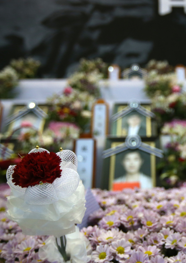 A carnation is placed in front of the photographs of the late Danwon High School teachers at an incense-burning altar set up at Ansan Olympic Memorial Hall in Ansan, Gyeonggi Province, on Teacher’s Day, May 15.   Yonhap