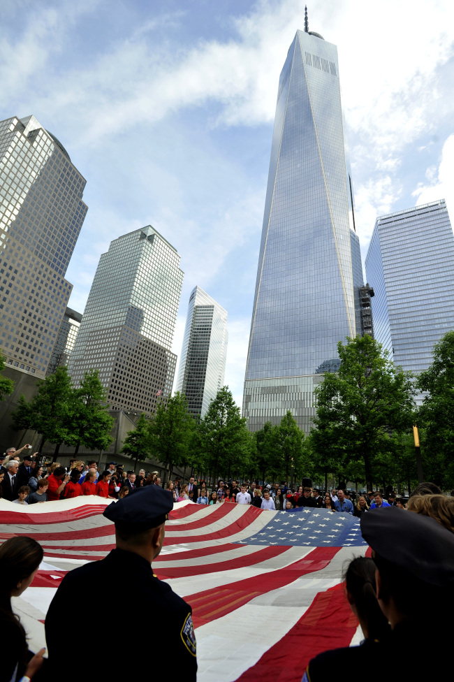 Firefighters, police and members of the military hold a U.S. flag in front of the National September 11 Memorial Museum in New York on Wednesday.   Xinhua-Yonhap