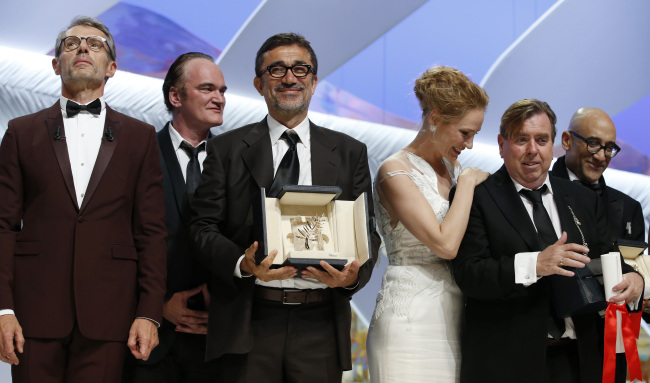 Turkish director Nuri Bilge Ceylan (center) poses with the Palme d’Or award after being awarded the top honor for his film “Winter Sleep” during the closing ceremony of the 67th Cannes Film Festival in Cannes, southern France, Saturday. Seen on stage with him are U.S. director Quentin Tarantino (second from left), U.S. actress Uma Thurman (third from right) and British actor Timothy Spall (second from right).   AP-Yonhap