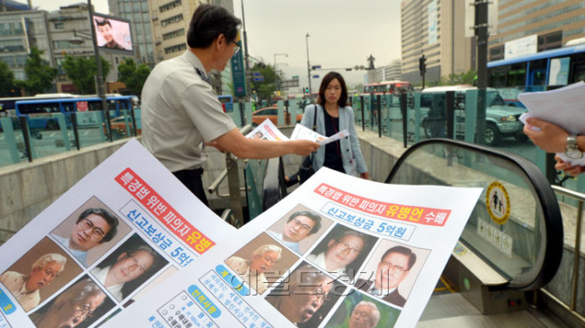 검찰이 유병언 회장에 대한 신고 보상금을 5천만원에서 5억원으로 형사범에 대한 신고포상금으로는 역대 최고액으로 올린 가운데 26일 오전 서울 광화문에서 종로경찰서 세종로파출소 소속 경찰관들이 수배전단을 시민들에게 나눠주고 있다.