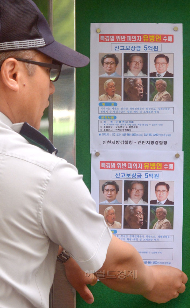 검찰이 유병언 회장에 대한 신고 보상금을 5천만원에서 5억원으로 형사범에 대한 신고포상금으로는 역대 최고액으로 올린 가운데 26일 오전 서울 광화문에서 종로경찰서 세종로파출소 소속 경찰관들이 게시판에 수배전단을 붙이고 있다.