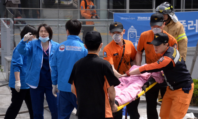 Firefighters carry an injured person after a fire broke out at the Goyang Bus Terminal in Goyang, Gyeonggi Province, Monday.   Ahn Hoon/The Korea Herald