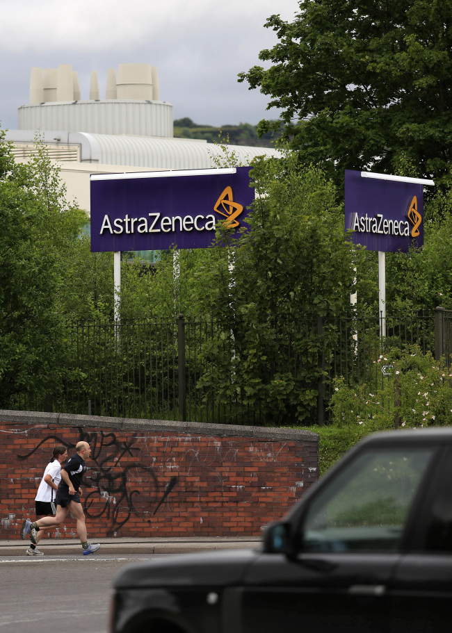 Joggers run past a sign outside  AstraZeneca Plc’s factory in Macclesfield, England.   Bloomberg