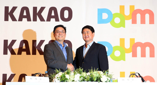 Daum Communications chief executive Choi Sae-hoon (left) and Kakao co-CEO Lee Sir-goo pose at a press meeting where the two sides announced the merger of the Internet portal and mobile messenger firms.   Yonhap