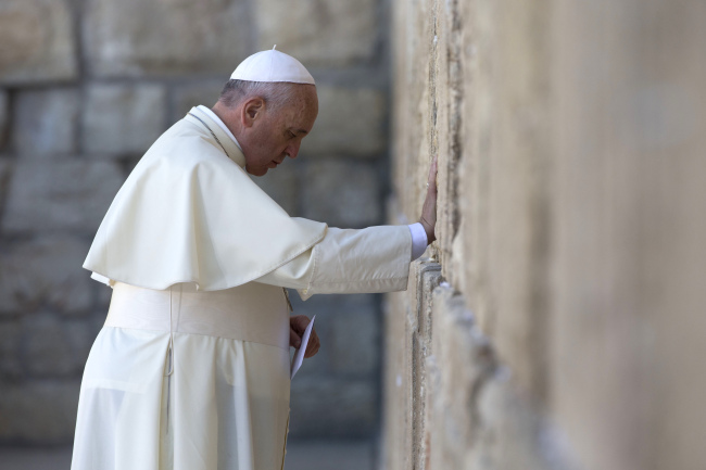 Pope Francis prays as he holds an envelope before placing it in on of the cracks between the stones of the Western Wall, the holiest place where Jews can pray, in the old city of Jerusalem, Israel, Monday.   AP-Yonhap