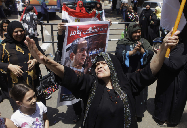 <YONHAP PHOTO-1855> An Egyptian voter dances as another holds a poster supporting presidential candidate Abdel-Fattah el-Sissi outside a polling station for the president election that comes nearly a year after the military's ouster of the nation's first freely elected president, the Islamist Mohammed Morsi in Cairo, Egypt, Monday, May 26, 2014. The man who removed Morsi, retired military chief Field Marshal Abdel-Fattah el-Sissi, is practically assured of a victory in the vote. (AP Photo/Amr Nabil)/2014-05-26 19:57:49/ <저작권자 ⓒ 1980-2014 ㈜연합뉴스. 무단 전재 재배포 금지.>
An Egyptian voter dances as another holds a poster supporting presidential candidate Abdel-Fattah el-Sissi outside a polling station for the presidential election in Cairo on Monday.   AP-Yonhap