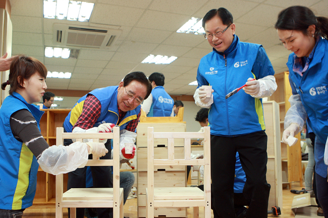 Shinhan Financial Group chairman Han Dong-woo (second from left) participates in the corporate volunteer project for building eco-friendly furniture to distribute to underprivileged households.   Shinhan Financial Group
