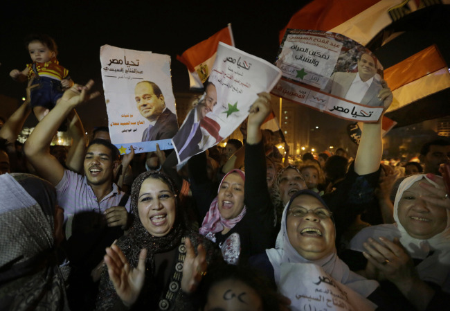 Supporters of Egypt’s former military chief Abdel-Fattah el-Sissi hold his posters during a celebration at Tahrir Square in Cairo on Thursday.   AP-Yonhap