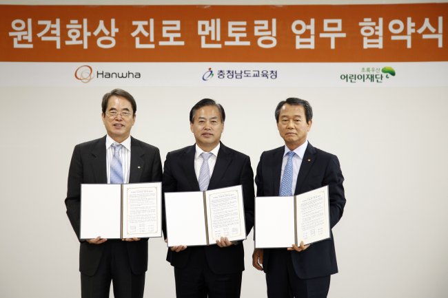 Hanwha S&C CEO Jin Hwa-keun (right), ChildFund Korea president Lee Je-hoon (left) and vice education chief of South Chungcheong Province Jeon Chan-hwan pose together in Seoul on Tuesday after signing an agreement to launch an online mentoring program for teenage students in rural areas.   Hanwha Group