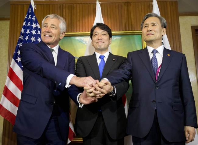 U.S. Defense Secretary Chuck Hagel (left), South Korean Defense Minister Kim Kwan-jin (right) and Japanese Defense Minister Itsunori Onodera shake hands prior to the start of their meeting in Singapore on Saturday.   AFP-Yonhap