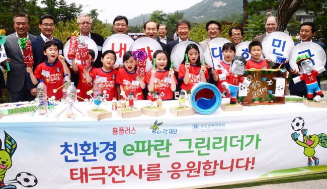 Homeplus CEO Do Sung-hwan (left, back row) and eParan Foundation’s board of directors head Lee Seung-han (sixth from left, back row) poses with kids and participants of a painting contest hosted by eParan on Sunday in central Seoul to celebrate World Environment Day on June 5. EParan is a social contribution organization run by Homeplus.   Park Hyun-koo/The Korea Herald