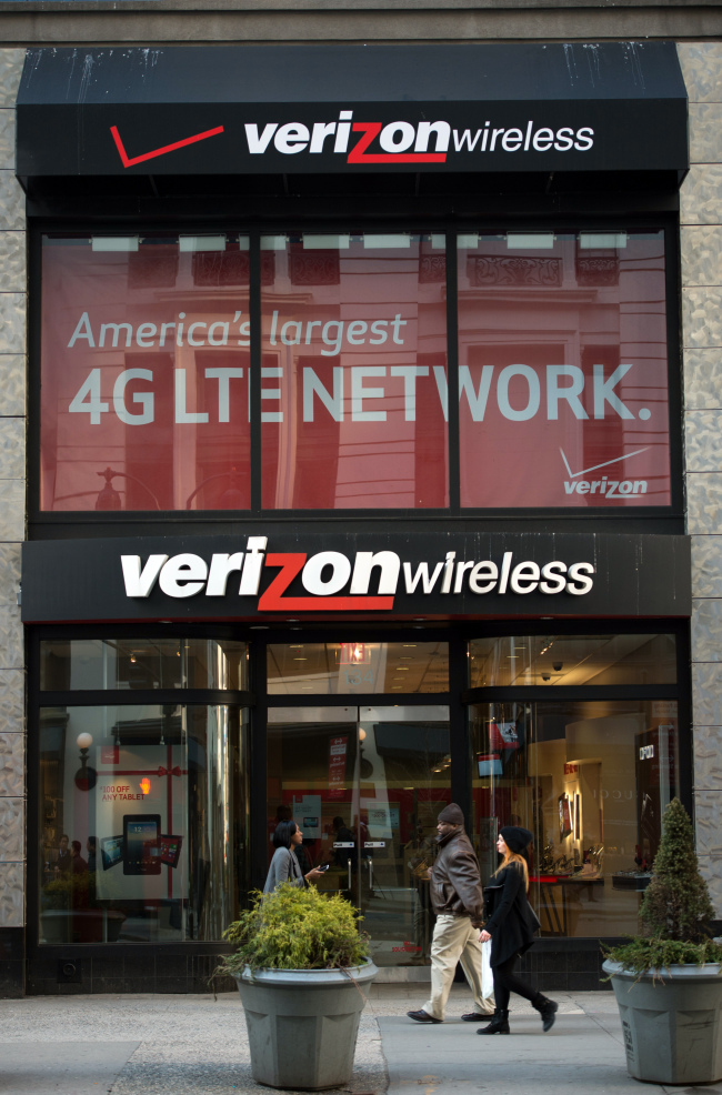 Pedestrians walk past a Verizon Wireless store in New York.   Bloomberg