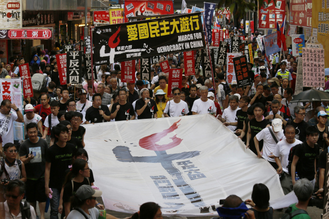 Thousands of Hong Kong residents march in downtown Hong Kong on Sunday, to mark the 25th anniversary of China’s bloody crackdown on Tiananmen Square on Wednesday, ahead of a much larger annual candlelight vigil. The huge white banner reads “Exonerate the June 4 protest.” (AP-Yonhap)