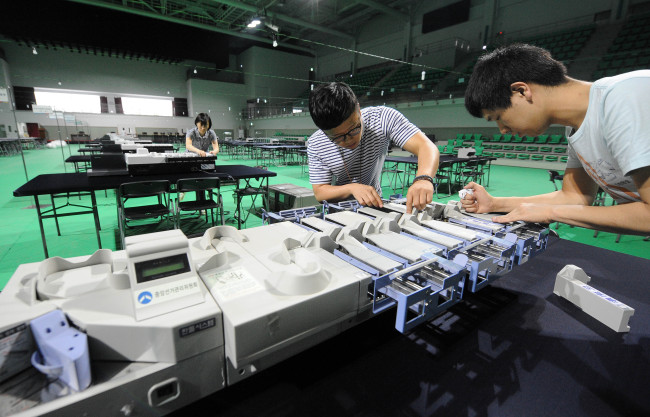 Officials from the National Election Commission’s Incheon branch office check an automated ballot counter at a gym in the city on Monday.   Yonhap