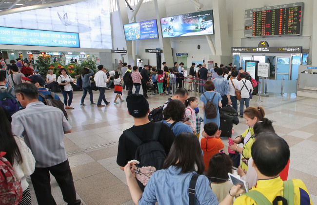 Travelers stand in line at Gimpo International Airport on Tuesday, a day before election day, which is a holiday.   Yonhap
