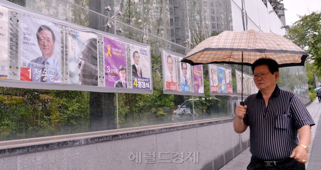 6·4 지방선거 하루를 앞둔 3일 오전 서울시 성동구 한 아파트단지 주변을 지나는 주민이 선거 벽보를 살펴보고 있다.