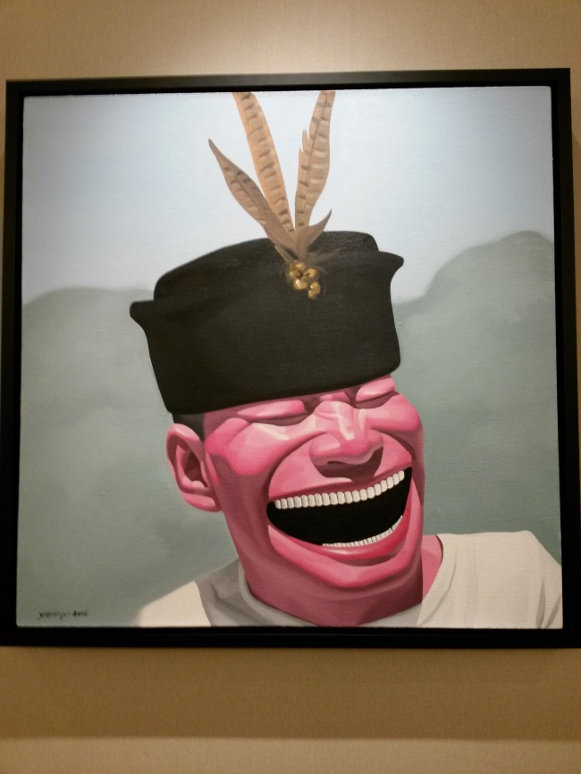 Chinese artist Yue Min-jun’s untitled work of a smiling man wearing a traditional Indonesian hat.   Philip Iglauer/ The Korea Herald