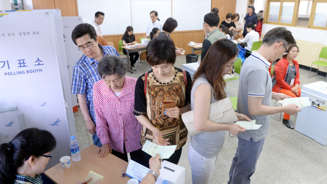 Voters stand in line at a polling station line in Yeouido, southeastern Seoul, Wednesday.   Ahn Hoon/The Korea Herald