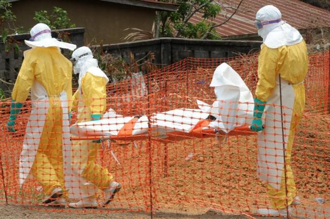 Staff of the ‘Doctors without Borders’ (‘Medecin sans frontieres’) medical aid organization carry the body of a person killed by the Ebola virus, at a center for victims of the hemorrhagic fever in Guekedou on April 1.   AFP