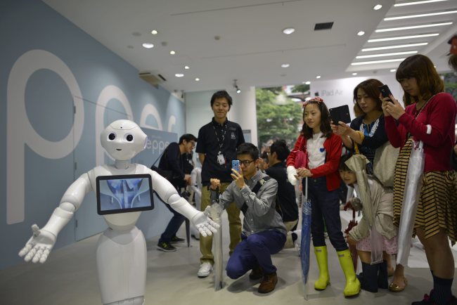 Visitors look at humanoid robot “Pepper” in Tokyo on Saturday.   EPA-Yonhap