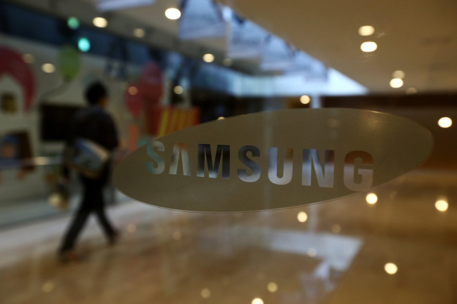 A man walks past a Samsung logo displayed at the group’s Seocho office building in Seoul.   Bloomberg