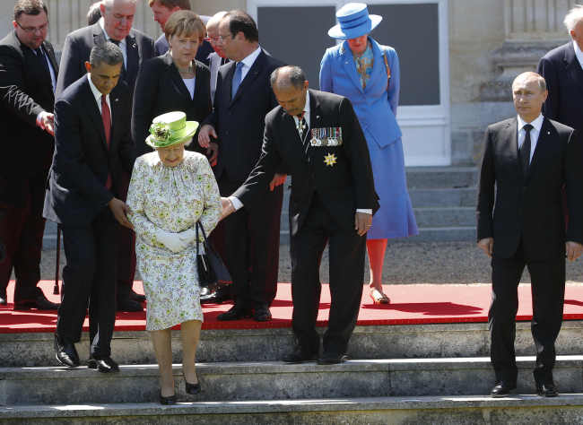 Russian President Vladimir Putin (right) stands by as U.S. President Barack Obama (left) and New Zealand’s Governor-General Jerry Mateparae guide Britain’s Queen Elizabeth II to her position for a group photo during commemorations for the 70th anniversary of the D-Day landings in Benouville in Normandy, France, Friday.   AP-Yonhap