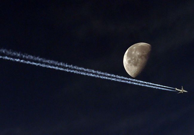 A jet passes in front of the moon in Algiers, Algeria.   AFP-Yonhap