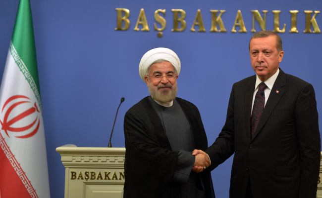 Iranian President Hassan Rouhani (left) and Turkey’s Prime Minister Recep Tayyip Erdogan shake hands in Ankara on Monday.   AP-Yonhap