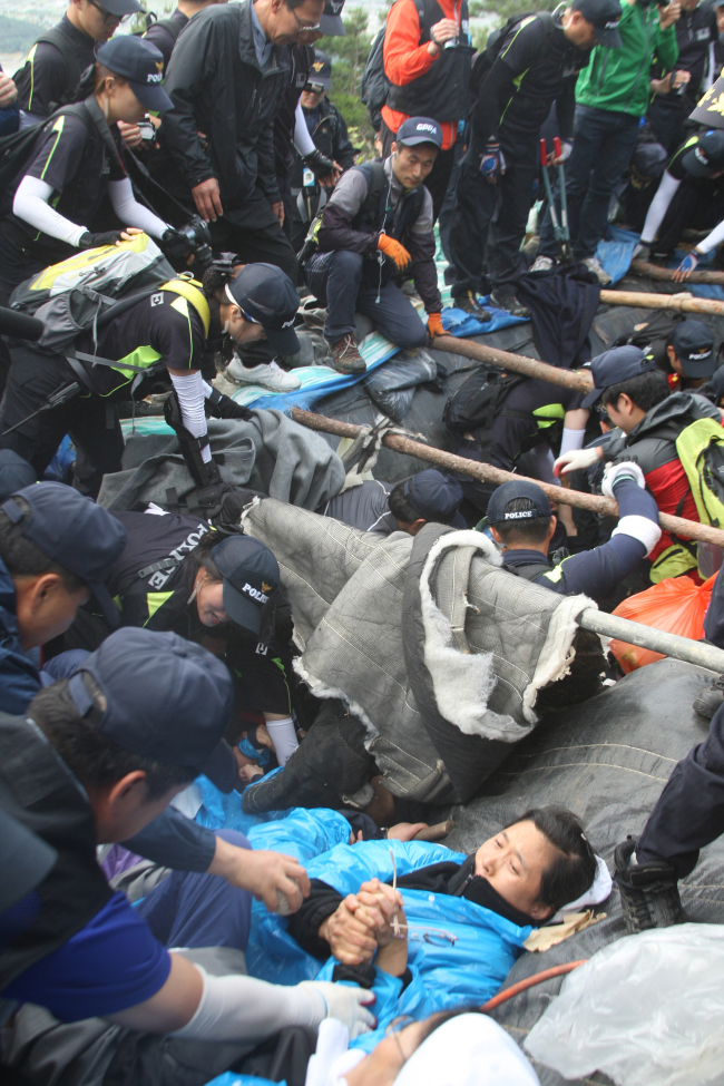 Police forcibly remove protesters blocking the path to the construction site of high-voltage transmission towers in Miryang, South Gyeongsang Province, Wednesday. (Yonhap)