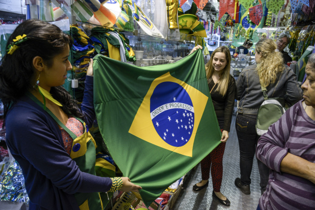 Customers hold up a Brazilian flag at a shop in Sao Paulo, Brazil.    Bloomberg
