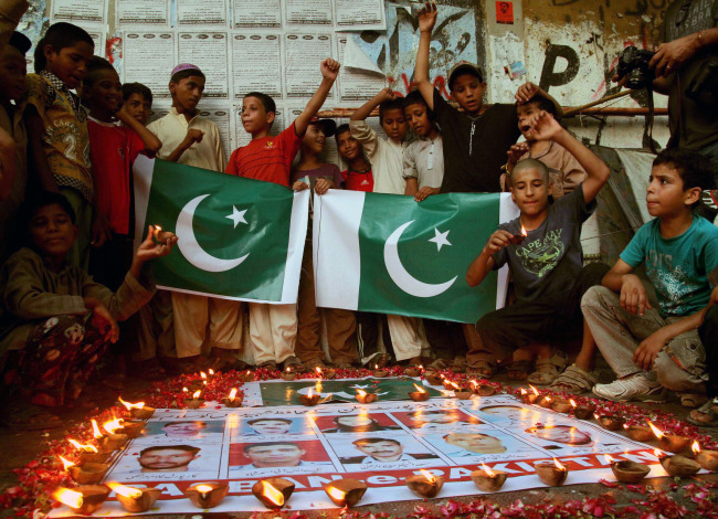 Pakistani people gather around pictures of security officials who were killed in an attack by militants on Karachi’s airport during a vigil ceremony in southern Pakistani port city of Karachi on Wednesday.   Xinhua-Yonhap