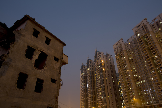 A partially demolished residential building (left) stands next to a Poly Real Estate Group Co. residential complex in the Zhujiang New Town district of Guangzhou, Guangdong province, China.   Bloomberg