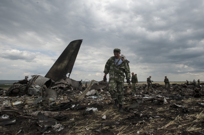 Pro-Russian fighters walk through the crash site of a Ukrainian army aircraft Il-76 at the airport near Luhansk, Ukraine, Saturday.   AP-Yonhap