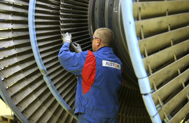 An Alstom employee measures the gap between blades on a turbine diaphragm at Alstom SA’s power plant turbine refurbishment facility in Rugby, England.   Bloomberg