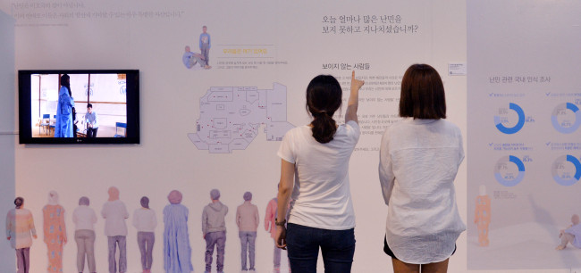 Citizens in front of Seoul City Hall on Wednesday look at exhibits displayed to celebrate World Refugee Day. The U.N.-designated commemoration date is this Friday.   Lee Sang-sub/The Korea Herald