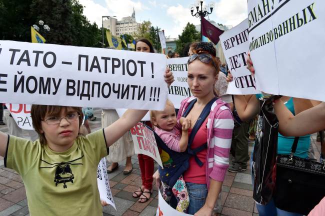 A young boy holds a banner reading “My father is a patriot! Give him rest!” as relatives and children of Ukrainian servicemen taking part in operations against pro-Russia separatists in eastern Ukraine demonstrate in front of the Ukrainian parliament in Kiev on Tuesday.   AFP-Yonhap