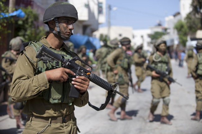 Israeli soldiers patrol during a search for three missing Israeli teenagers in the village of Taffouh near the West Bank city of Hebron on Wednesday.   AP-Yonhap