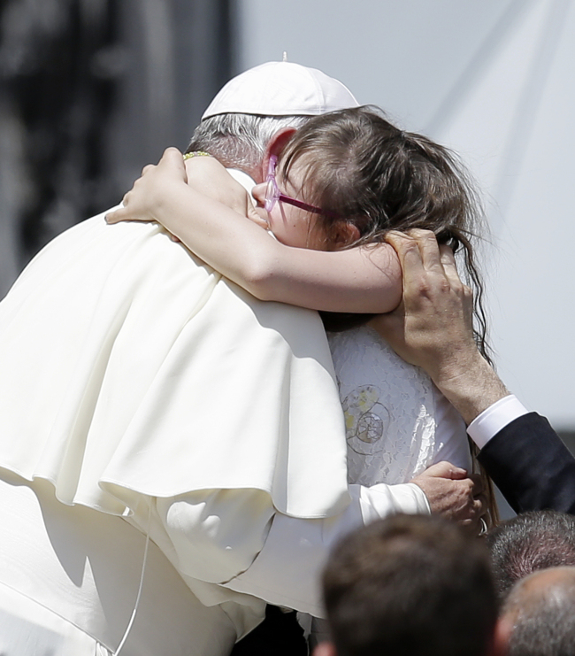 Pope Francis is hugged by a child at the end of his weekly general audience in St. Peter’s Square at the Vatican, Wednesday.   AP-Yonhap