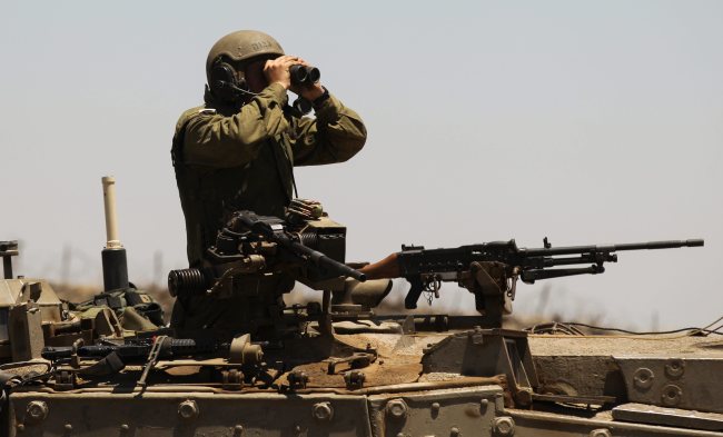 An Israeli soldier uses binoculars from a Merkava tank on the Israeli-Syrian border near Quneitra in the center of the Golan Heights on Sunday.   EPA-Yonhap